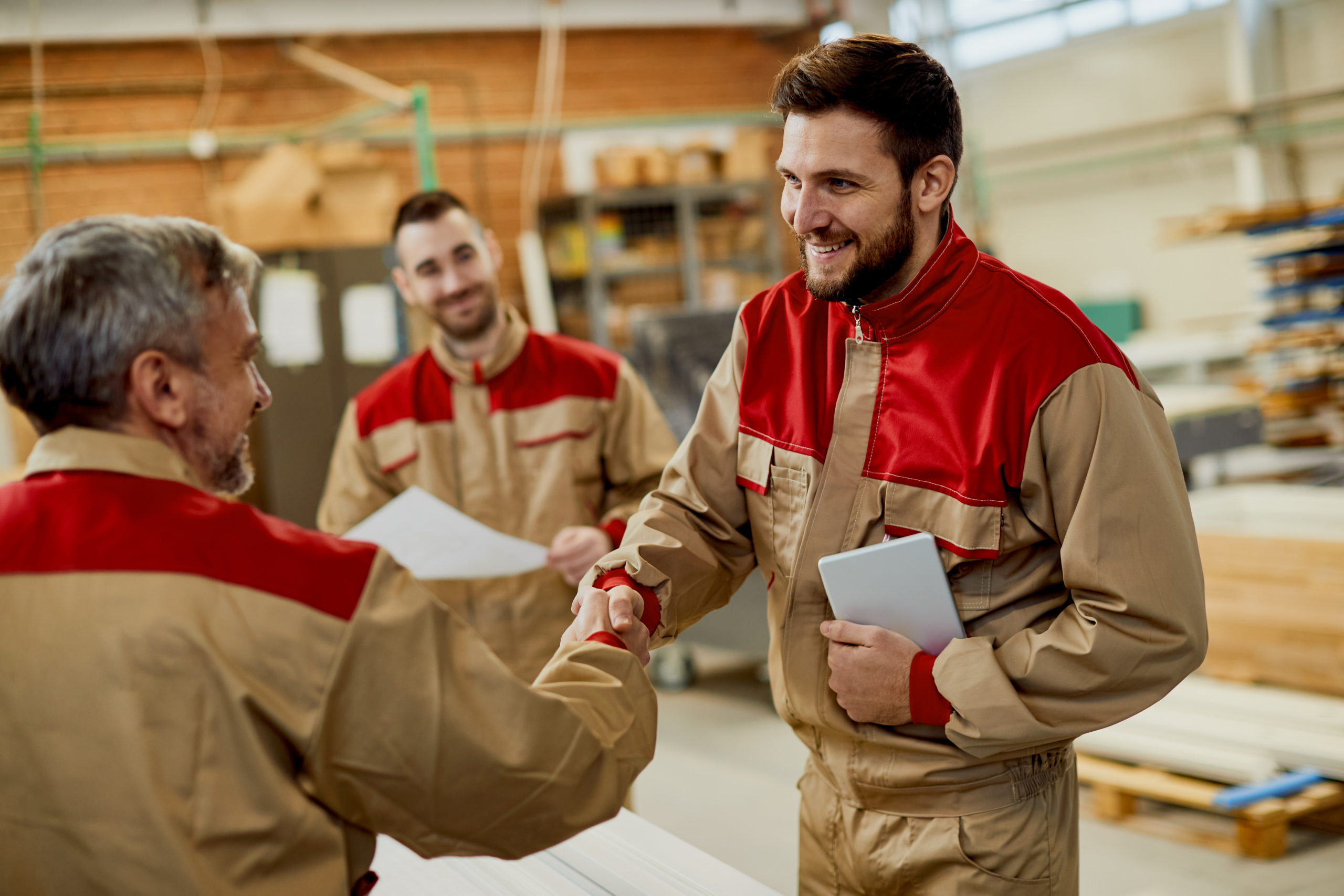 Happy carpenter handshaking with is colleague while greeting in